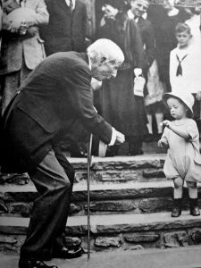 Rockefeller gives a nickel to a child on his 84th birthday, 1923.