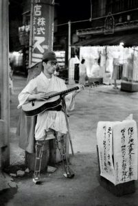 War survivor plays guitar on the streets of Asakusa, 1950s.