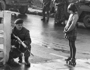 Curious little girl on roller skates interrupts army patrol during the Battle of the Bogside, Northern Ireland, 1969 