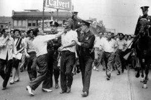 Police try to escort a black man to safety during the Detroit Race Riot of 1943. 