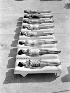 Fashion models relaxing near a pool in Miami, Florida, 1956.