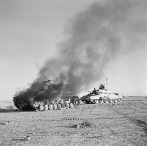 A British Crusader passes a burning Panzer IV during Operation Crusader; 27 November 1941 