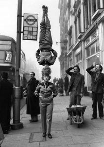 Circus performers head-to-head walk at Hammersmith Broadway, London, 1953.