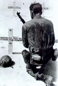 A US Marine kneels over the grave of a fallen friend. September, 1944. 