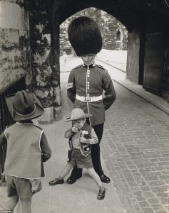 Young boy poses in front of a Queen's Guard in London. 1960s.