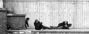 (Northern Ireland, 1972) IRA freedom fighters pinned down by the Royal Army. The fighters are next to graffiti that reads, 