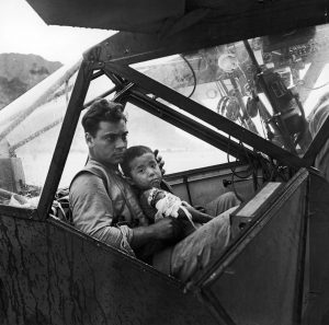 An American pilot holds a wounded Japanese boy during the WW2 Pacific battle on the island of Saipan as they await to fly to the nearest field hospital, 1944. 