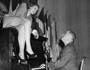 Film star Lauren Bacall atop a piano while Vice President Harry Truman plays (2/10/1945)