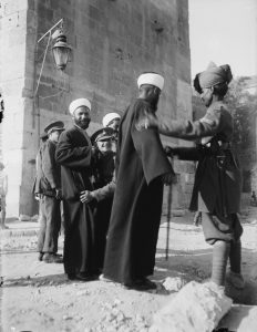 British Police search Arab civilians in Jerusalem, shared laughs, 1920.