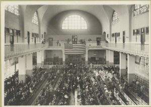 Immigrants seated on long benches, Main Hall, Ellis Island, ca.1907-1912 