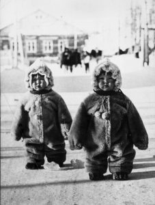 Twin toddlers, bundled up, waddle like penguins in Russia, 1968.