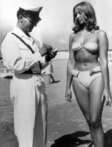 Officer ticketing a woman for wearing a bikini, Italy, 1957.