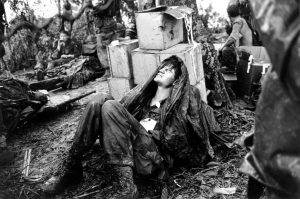 A wounded U.S. paratrooper grimaces in pain while waiting for medical evacuation at base camp in the A Shau Valley near the Laos border in South Vietnam during the Vietnam War. Photo taken by then AP photographer Hugh Van Es on May 19, 1969.