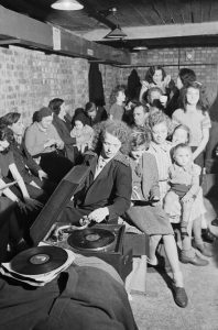 Young woman plays a gramophone in an air raid shelter in London, 1940.