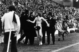 Michael O'Brien, first known streaker at a major sporting event, has his modesty covered by helpful policeman. Rugby match at Twickenham, 20 April 1974. 